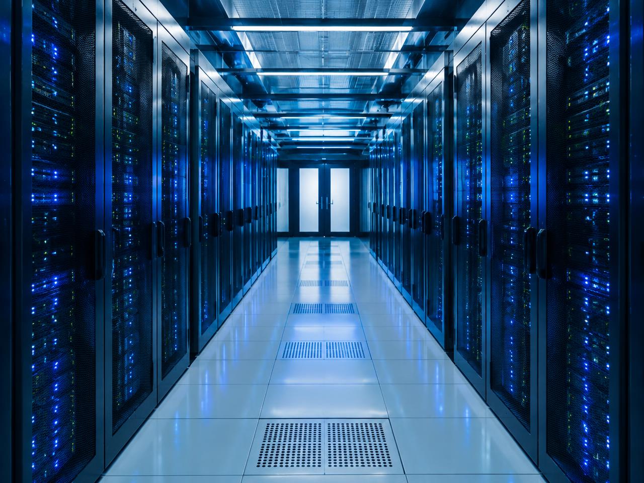 Stock photo: a symmetrical data centre corridor lined with server racks glowing blue